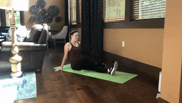 female demonstrating glute stretch seated with knee up and opposite leg crossed