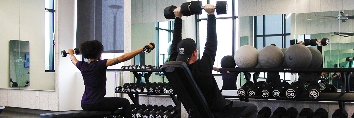 a man and a woman lifting weights in the frisco fitness center