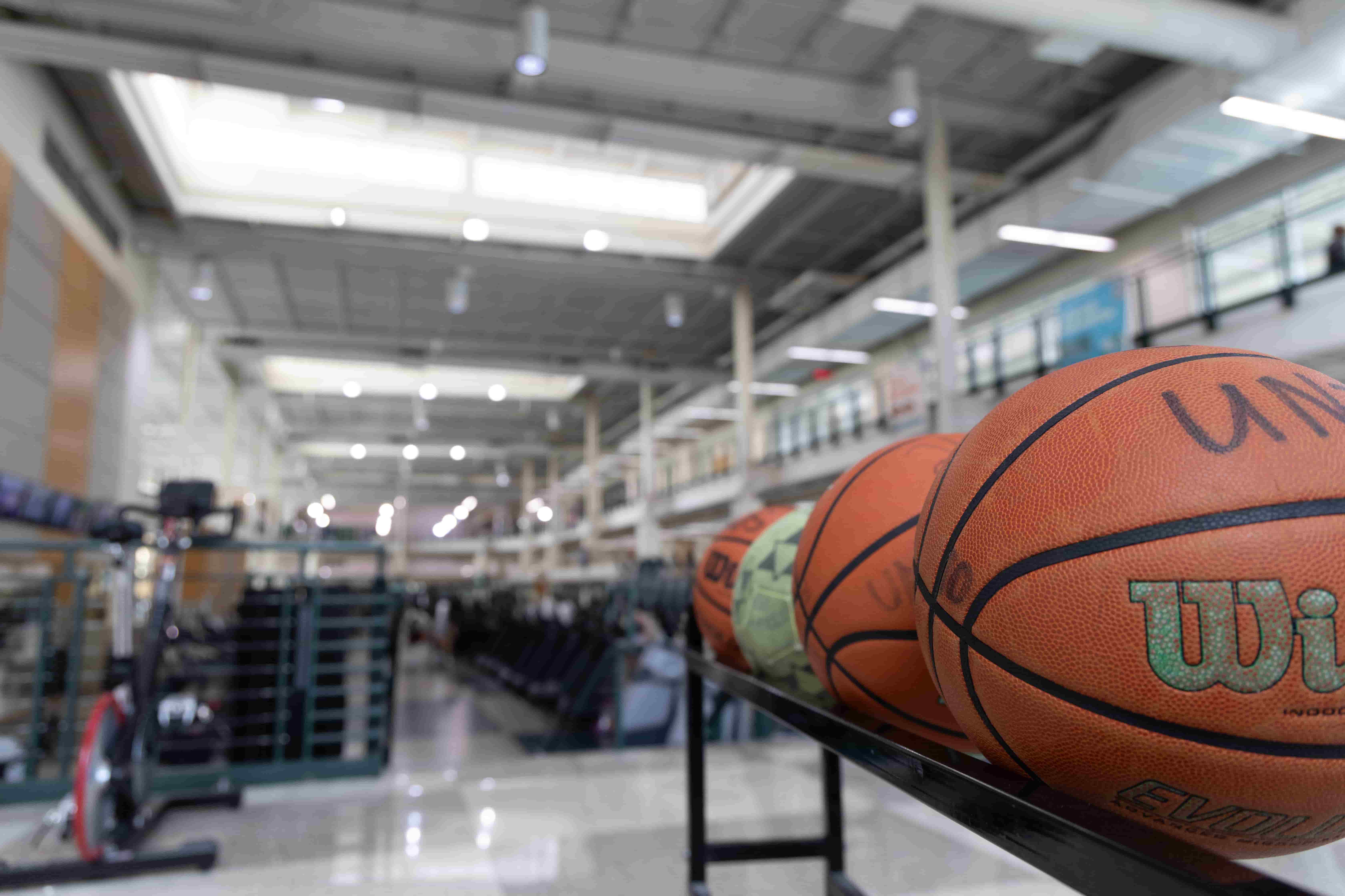 Basketballs resting on a rack. The main weight room is in the background.