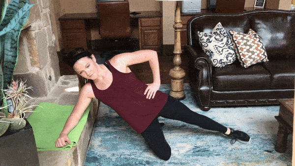 woman demonstrating side plank with leg lift on incline