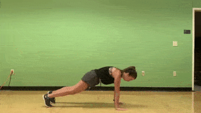 female demonstrating plank push + opposite knee tap