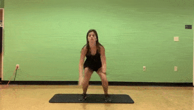 female demonstrating squat jump to step back